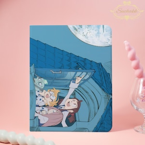 May include: A blue tablet case featuring an anime-style illustration of three characters in a vehicle, with a large moon in the background. The characters are smiling and pointing upwards. The Suchakk logo is in the upper right corner.