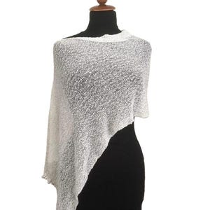 Może przedstawiać: Biały ponczo z dzianiny o luźnym, swobodnym kroju. Ponczo wykonane jest z lekkiej, przewiewnej tkaniny i ma prosty, elegancki design.