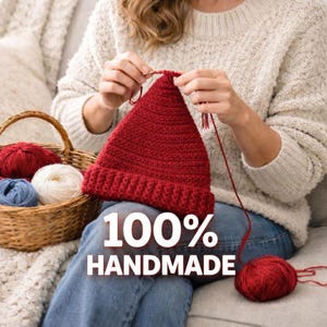 May include: A red knitted beanie is being crafted with red yarn. A basket holds red, white, and blue yarn balls. The text "100% HANDMADE" is displayed on the image, emphasizing the handcrafted nature of the item.