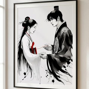 Op de afbeelding: Zwart-wit ingelijste kunstdruk met een stel in traditionele Aziatische kledij. Het kunstwerk toont een man en een vrouw die elkaars handen vasthouden, verbonden door een rode draad. De vrouw draagt een witte jurk met rode accenten, de man een zwarte jurk.