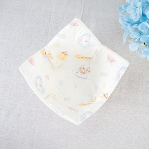 Puede incluir: Un cuenco de tela blanca con un estampado caprichoso de postres, corazones y estrellas en colores pastel. El cuenco tiene forma cuadrada y parece estar doblado. El tema general es un diseño lindo y juguetón.