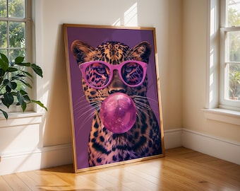 May include: A framed wall art print featuring a leopard with a spotted coat, wearing bright pink glasses and blowing a large, round pink bubblegum bubble. The background is a solid deep purple, and the artwork is encased in a thin gold frame.