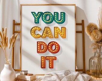 Puede incluir: Un cartel enmarcado con las palabras "YOU CAN DO IT" en letras luminosas tridimensionales y coloridas. Las letras son turquesa, amarillo-naranja y rojo, cada una con pequeñas luces redondas amarillas. La obra de arte se muestra sobre un fondo blanco.