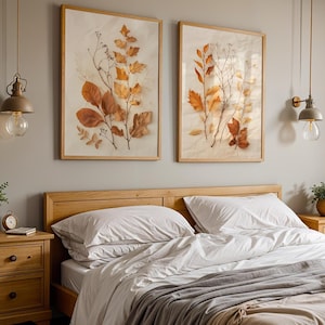 The two framed pressed leaf botanical prints hang on a grey wall above a wooden bed frame with white and grey bedding, flanked by matching nightstands.
