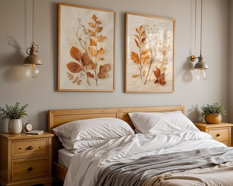 The two framed pressed leaf botanical prints hang on a grey wall above a wooden bed frame with white and grey bedding, flanked by matching nightstands.