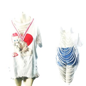 Puede incluir: Camiseta blanca con un coraz&oacute;n rojo y un gatito blanco. La camiseta tiene un ribete de encaje rosa y est&aacute; desgastada con recortes.