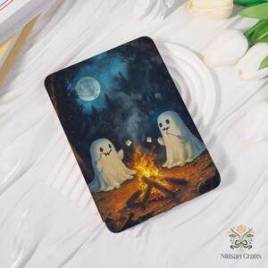 May include: A rectangular art print depicting two cartoon ghosts toasting marshmallows over a campfire. The background shows a dark forest under a full moon. The print has a whimsical, Halloween theme.