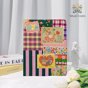Puede incluir: Una cubierta de cuaderno estilo patchwork con varios patrones de tela, incluyendo cuadros, flores y rayas. Tarjetas de San Valentín de estilo vintage están pegadas en la cubierta, con frases como "I Love You" y "Can you Bear to be my Valentine?"