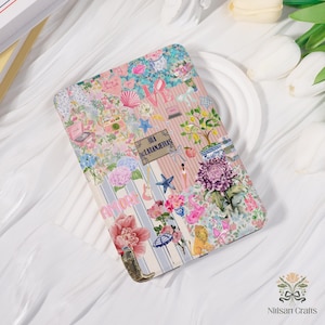 May include: A rectangular case with a colorful floral and patterned design. The case features a collage of flowers, seashells, and the word "AMORE". The case has a pink and blue striped background with the text "RUA LARANJEIRAS".