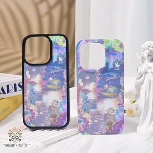 May include: Two phone cases with a fantasy landscape design. The cases feature a black border and a colorful print of a mythical scene with figures, a lake, and a horse. The cases are decorated with a variety of colors, including purple, blue, and pink.