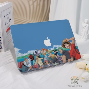 Może przedstawiać: Niebieskie etui na laptopa z kolorową ilustracją anime przedstawiającą grupę postaci w biegu. Projekt zawiera białe logo Apple i tło z chmurami i wodą. To ochronne akcesorium.