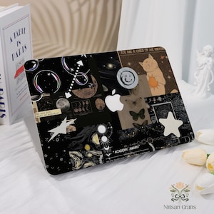 Op de afbeelding: Zwarte laptophoes met een collage-ontwerp met hemelse elementen, een kat met een zon, vlinders en het Apple-logo. Tekst bevat "We are all made of stardust" en "You are a child of the universe."