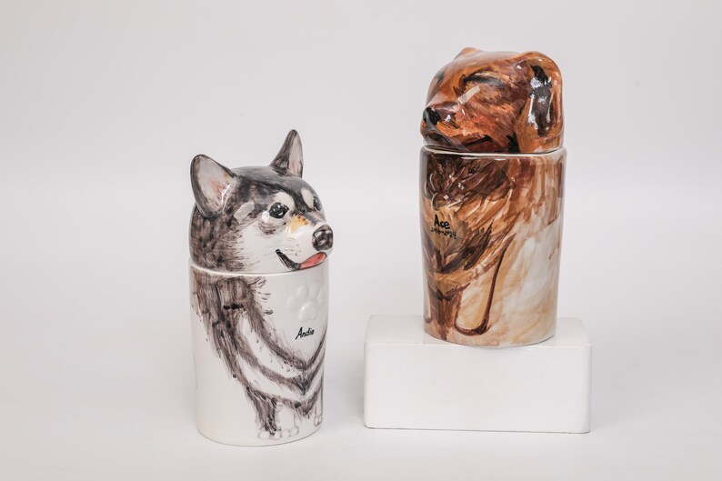 May include: Two ceramic dog-themed containers. One features a husky design with black, white, and gray fur, and the name "Anda". The other has a brown dog design with the name "Ace".
