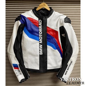 May include: White leather motorcycle jacket with black detailing and blue and red stripes. The jacket has "BMW MOTORRAD" printed down the front and on the sleeves. The brand name "VESTRON LEATHER" is printed at the bottom.
