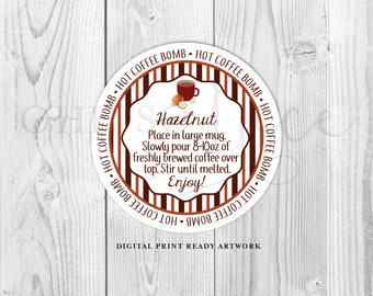 May include: A circular label with a brown and white design, featuring the text "Hot Coffee Bomb" around the edge. The label includes the word "Hazelnut" and instructions for use. A small illustration of a coffee cup and hazelnut is included. The words "Digital Print Ready Artwork" are at the bottom.