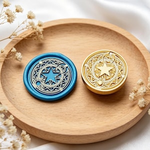 Peut inclure: Un sceau en cire bleu circulaire orné d'une étoile dorée et de motifs géométriques célestes, accompagné d'une tête de sceau en métal doré présentant le même motif complexe d'étoile et de croissant de lune.