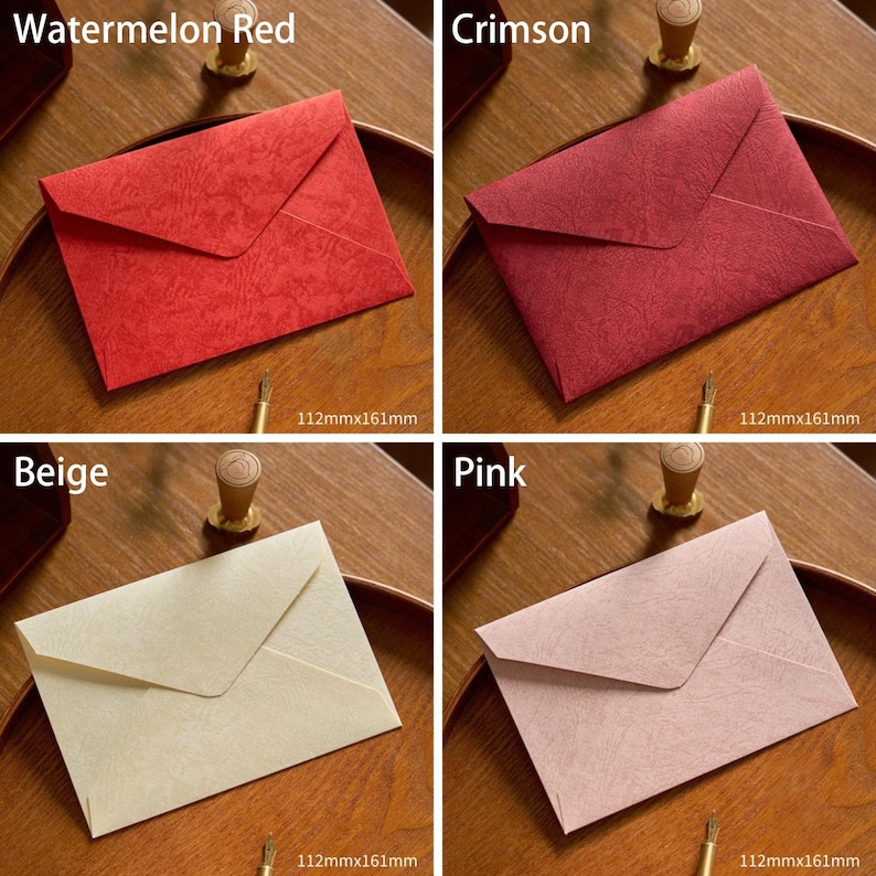 May include: Four colorful envelopes in watermelon red, crimson, beige, and pink. Each envelope is 112mm x 161mm. The envelopes are displayed on a wooden surface. The envelopes are for stationery and correspondence.