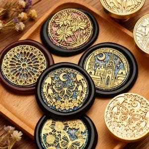 May include: A collection of decorative wax seal stamps with intricate gold designs. The stamps feature floral, butterfly, and architectural motifs. The seals are set on a wooden tray, showcasing their detailed craftsmanship and artistic appeal.