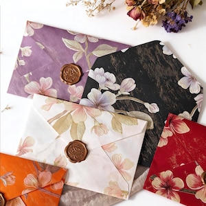 May include: A selection of floral-patterned envelopes in shades of purple, black, white, orange, and red. Each envelope is sealed with a brown wax seal. The envelopes feature a floral design.
