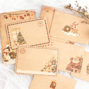 May include: A collection of Christmas-themed stationery, including envelopes and a large sheet. The envelopes feature festive illustrations of Santa Claus, Christmas trees, reindeer, and snowmen. The color palette includes brown, red, green, and white.