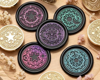 May include: A collection of circular wax seal stamps and finished wax seals featuring intricate celestial designs with stars, moons, and suns. The seals are rendered in metallic gold, solid black with pink, purple, and teal accents, and a wooden handle.