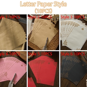 May include: A collection of letter paper in various styles and colors. The image shows six different stacks of paper, each with a unique design. The paper colors include brown, beige, white, pink, red, and black. Each sheet has a decorative border.