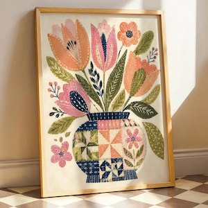May include: A framed art print featuring a bouquet of stylised peach, pink, and orange tulips with green leaves in a round vase. The vase displays a multi-coloured patchwork quilt pattern with blue, pink, and orange geometric squares and floral motifs.