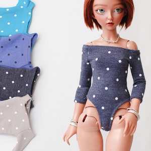 May include: A set of four doll-sized tops with white polka dots on a blue, indigo, dark blue, and gray background. The tops are all sleeveless and have a scoop neck.