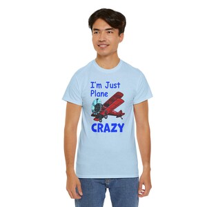 May include: A light blue t-shirt with a red airplane graphic and the text "I'm Just Plane Crazy" in blue.