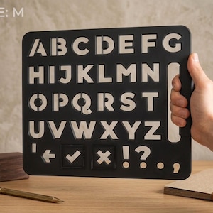 May include: A black rectangular stencil featuring the uppercase English alphabet from A to Z, along with punctuation marks including an arrow, checkmark, X, exclamation point, question mark, period, and comma. The stencil is labeled with the text SIZE: M.