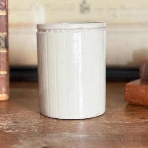 May include: A set of three ceramic mugs with a speckled, matte finish. The mugs are in shades of cream, light gray, and dark gray. Each mug has a simple, minimalist design and a rounded handle.