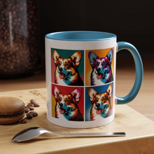 May include: A white ceramic mug with a blue rim and handle. The mug features a pop art design of four colorful corgi dogs.
