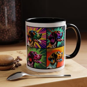 May include: A white ceramic mug with a black rim and handle. The mug features a pop art design of four German Shorthaired Pointers in different colors and poses.