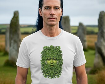 Op de afbeelding: Wit t-shirt met een gedetailleerde groene illustratie van de Green Man, een gezicht gemaakt van bladeren en gebladerte. Het ontwerp is gecentreerd op het t-shirt, gedragen door een persoon in een veld met stenen structuren op de achtergrond.