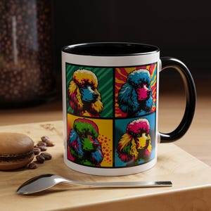 May include: A white ceramic mug with a black rim and handle. The mug features a pop art design of four colorful poodle dogs in different poses.