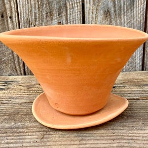 May include: A white ceramic mug with a black handle and the text "But First, Coffee" in a bold, black font. The mug is set against a blurred background, suggesting a cozy setting. The mug appears to be approximately 4 inches tall.