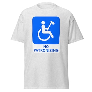 Puede incluir: Una camiseta gris con un gráfico azul y blanco de una persona en silla de ruedas sosteniendo un hacha. El texto "NO PATRONIZING" está debajo del gráfico.