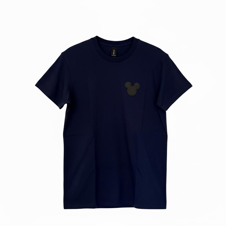 Puede incluir: Camiseta azul marino con un peque&ntilde;o gr&aacute;fico de la cabeza de Mickey Mouse en gris oscuro en el pecho. La camiseta de manga corta est&aacute; hecha de un material suave y tiene un dise&ntilde;o cl&aacute;sico de cuello redondo. Una camiseta sencilla e informal para el d&iacute;a a d&iacute;a.