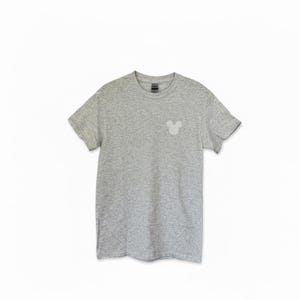 Puede incluir: Una camiseta gris jaspeado con un peque&ntilde;o gr&aacute;fico de la cabeza de Mickey Mouse en gris claro en el lado izquierdo del pecho. La camiseta de manga corta tiene cuello redondo y est&aacute; hecha de un material suave y c&oacute;modo. Un estilo cl&aacute;sico y casual.
