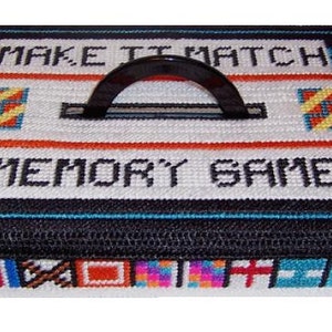 May include: A black and white memory game box with a black handle. The box has a colorful design on the bottom and the text "Make It Match Memory Game" on the top.