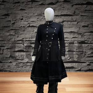 Può includere: Un cappotto nero a maniche lunghe con colletto alto, cintura e fondo a gonna. Il cappotto ha una chiusura a doppio petto con bottoni argentati.