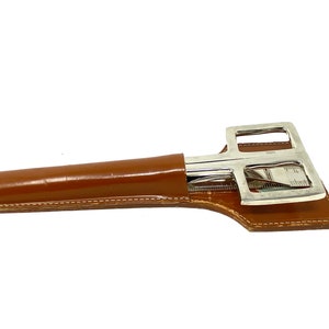 May include: A silver-toned multi-tool with a leather case. The tool has a ruler, a knife, and a pair of scissors.