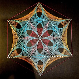 May include: A geometric string art piece with a hexagonal shape. The design features a central star with six points, surrounded by a series of concentric circles and lines. The string is red, orange, and blue.