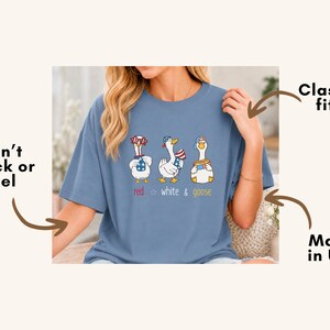 Puede incluir: Camiseta azul claro con un gr&aacute;fico de tres gansos de dibujos animados con atuendos patri&oacute;ticos. El texto "red white & goose" est&aacute; debajo. Corte cl&aacute;sico, fabricado en EE. UU.