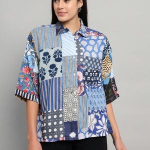May include: A button-down shirt featuring a patchwork design with various blue and white patterns, including floral motifs, stripes, polka dots, and geometric shapes. The shirt has a classic collar, a front button placket, and elbow-length sleeves.