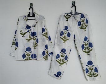 May include: White pajama set with a blue floral pattern. The set includes a button-down shirt with a chest pocket and long pants. The floral design features blue flowers and green leaves.