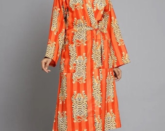 May include: An orange robe with vertical stripes and a repeating tiger print. The robe has long sleeves and a wrap-around design with a matching belt. The model is wearing the robe.