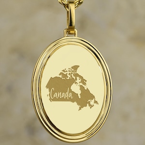 Könnte beinhalten: Vergoldete Halskette mit Anhänger, die eine detaillierte Karte von Kanada zeigt. Der runde Anhänger hat einen doppelten Rahmen und eine Seilkette. Das Wort "Canada" ist auf dem Anhänger eingraviert. Es ist ein Schmuckstück.