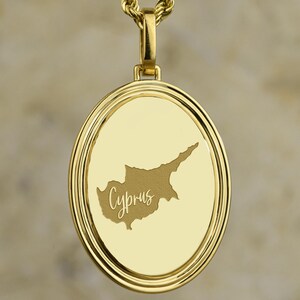 Op de afbeelding: Goudkleurige hangerketting met een gedetailleerde omtrek van Cyprus. De hanger heeft een gepolijste afwerking en het woord "Cyprus" is in een cursief lettertype gegraveerd. De ketting heeft een gedraaid touwontwerp.