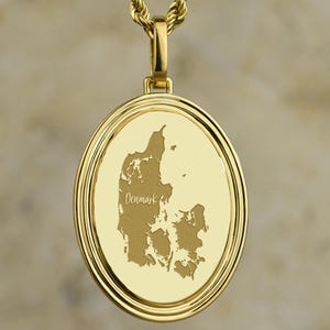 May include: A gold-colored pendant necklace featuring a detailed map of Denmark. The pendant is round with a raised border and the word "Denmark" engraved. The necklace chain is a twisted rope design.